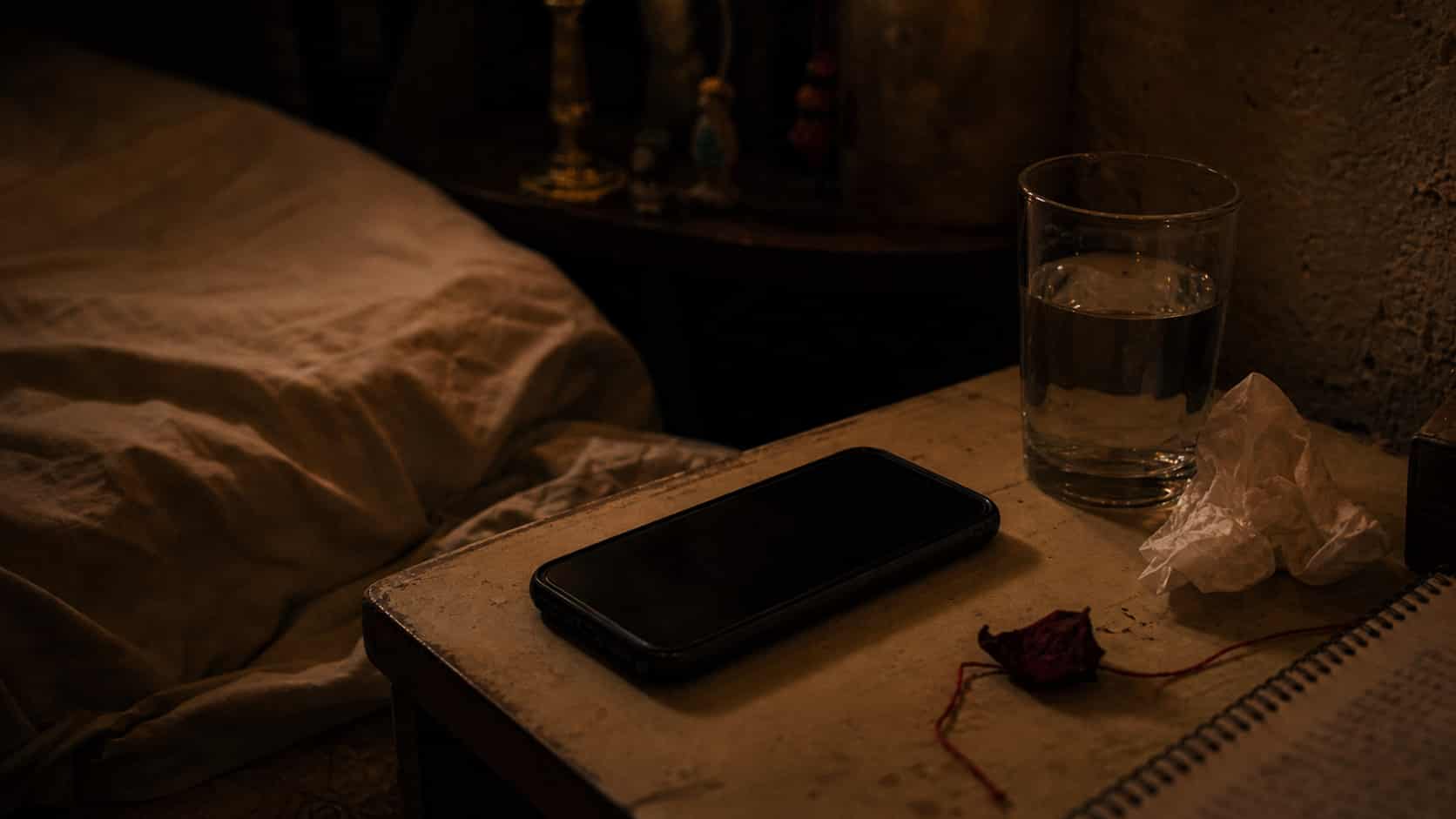 Mesa de noche con un teléfono en silencio, esperando un mensaje